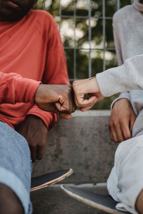 photo of two guys on skateboards fistbumping