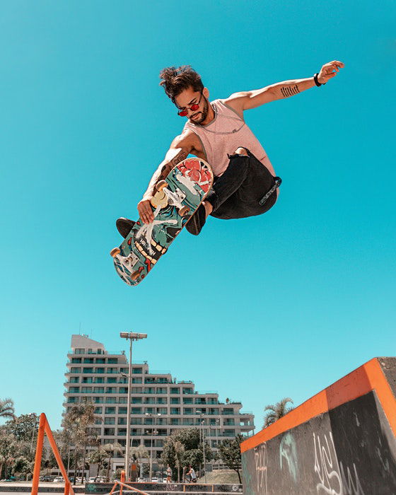 photo of a jumping skateboarder against the blue sky