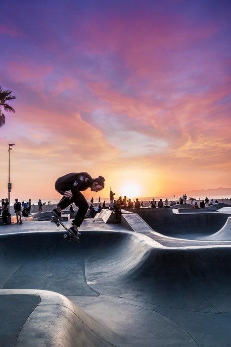 photo of a skateboarder jumping at sunset