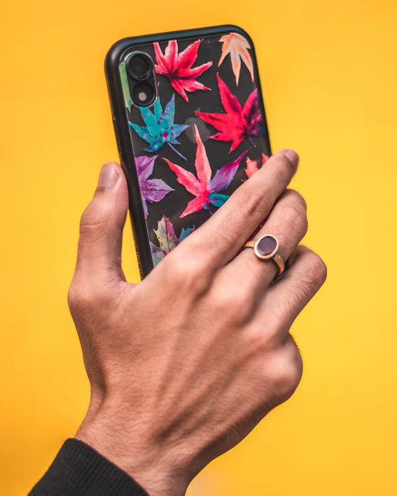 A person holding a smartphone with a brightly colored case