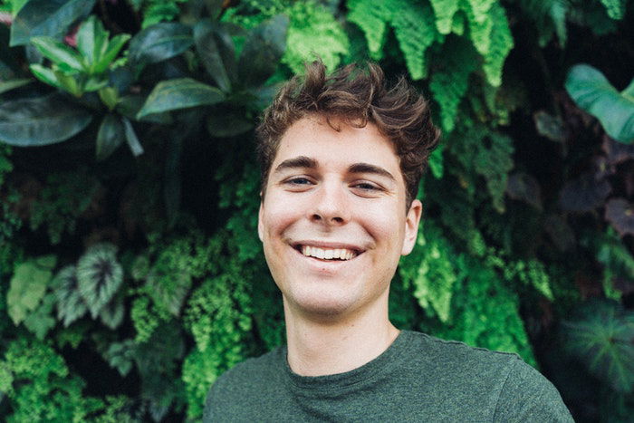 A young man infront of a green background