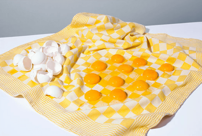 modern still life photo of egg yolks placed on a piece of cloth resembling a checker board