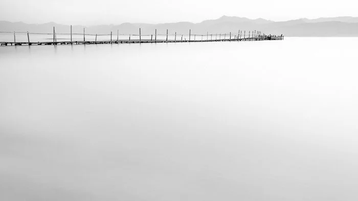 Minimal photo of a dock in Kalamaki beach at dawn in Kerkyra Greece demonstrating smooth motion blur