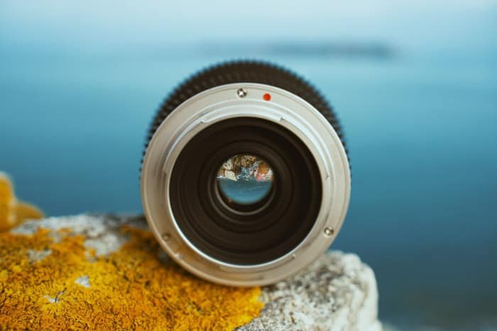A camera lens on a wall in front of the ocean
