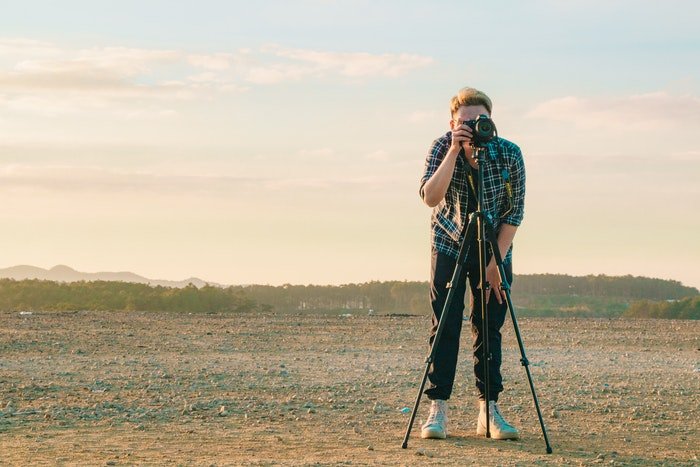 A photographer setting up a shot with DSLR on a tripod