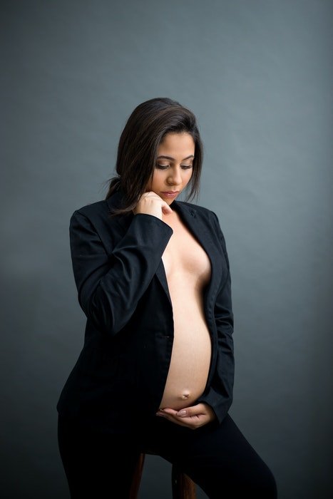 Beautiful maternity boudoir photo of a pregnant woman posing in a studio