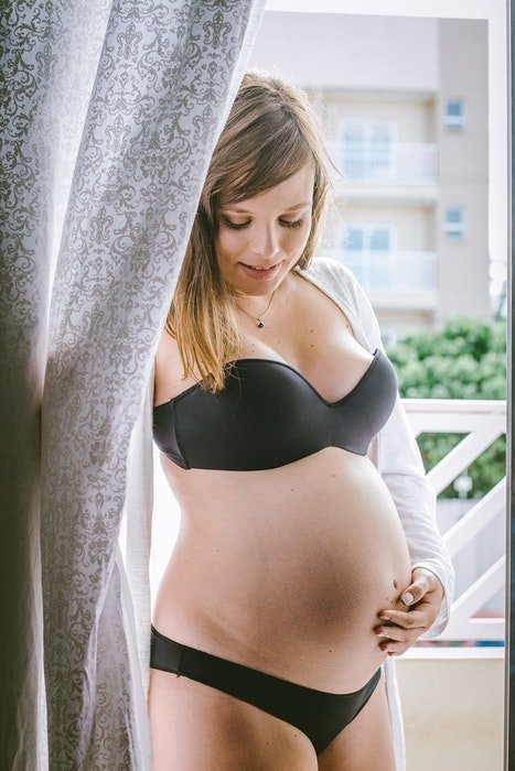 Beautiful maternity boudoir photo of a pregnant woman posing in lingerie