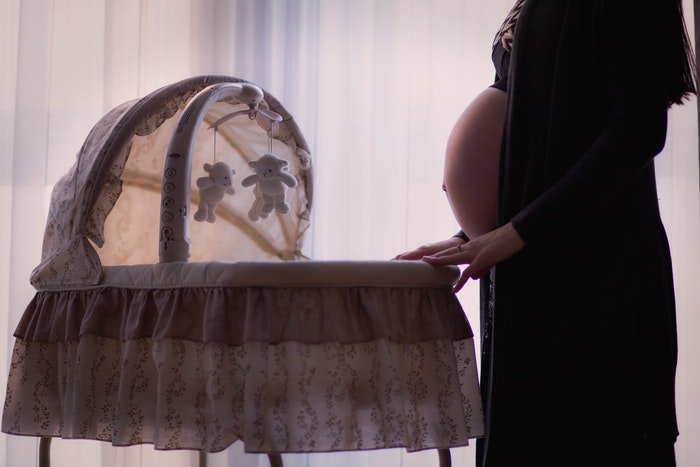 Beautiful maternity boudoir photo of a pregnant woman rocking a cradle