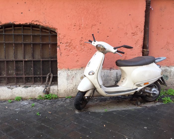 a Vespa motorbike on a street corner in Rome