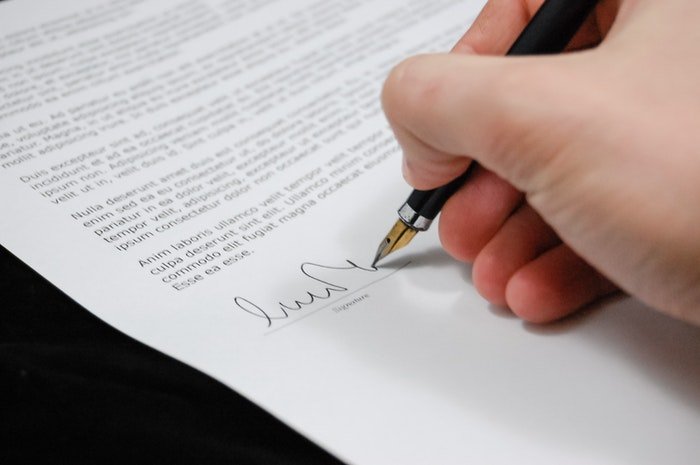 A close up of a person signing real estate photography terms and conditions