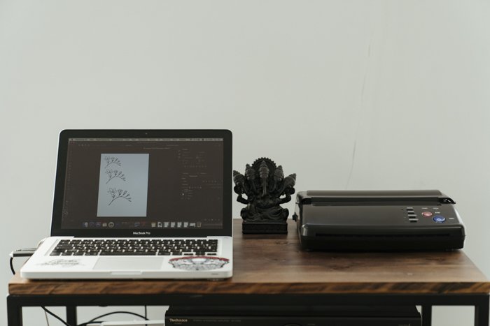 A laptop and printer on a wooden desk