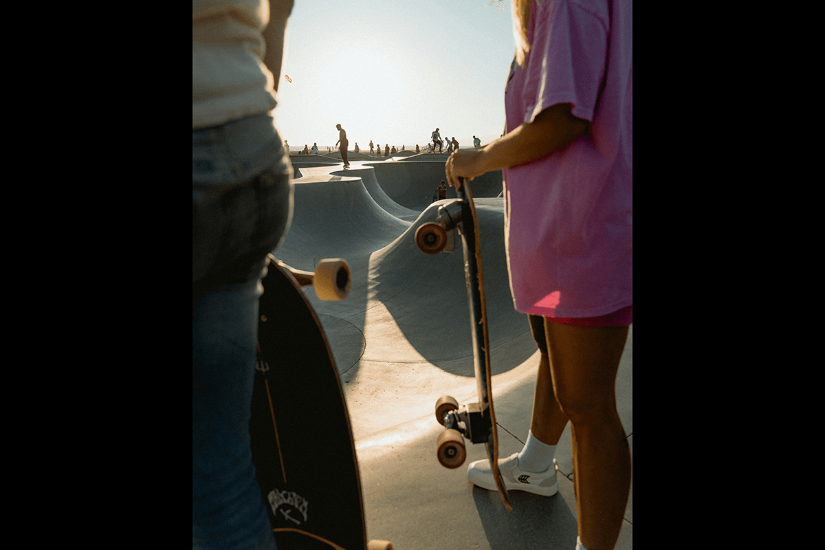 Two skateboarders holding onto boards with skaters in the background as an example of skateboard photography