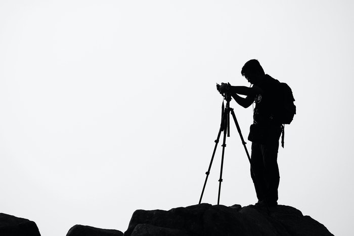 Silhouette of a photographer setting up his camera on a tripod