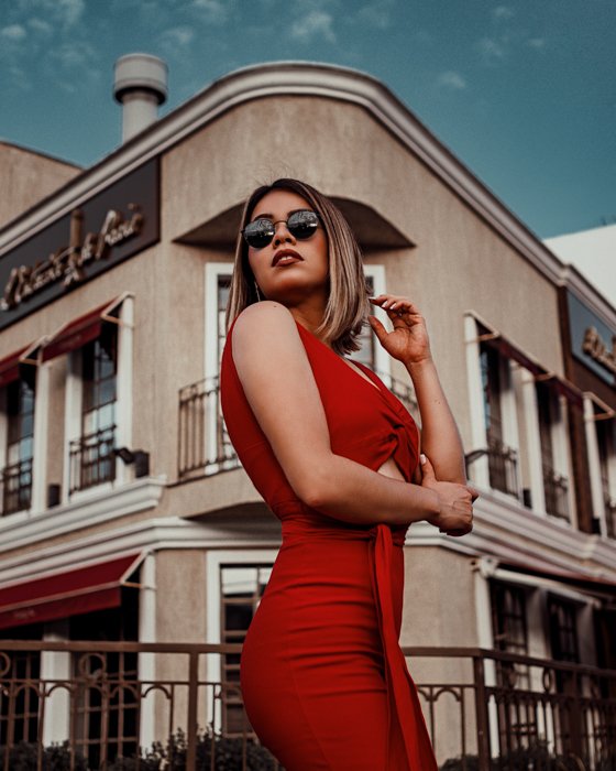 portrait of woman in red dress posing in front of a building