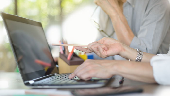 Businesspersons discussing and pointing at screen in office