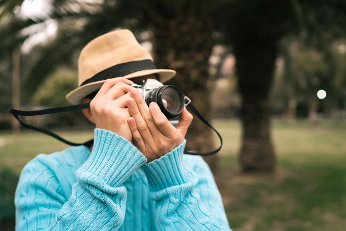 Portrait of young asian tourist with a vintage camera and taking some photos outdoors in the street. 