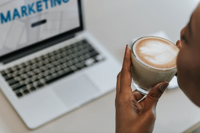 Woman sipping a cup of coffee while working on a laptop