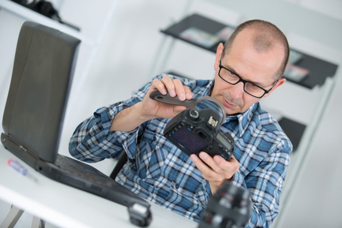 Repairman looking at fungus on a camera lens through magnifying glass