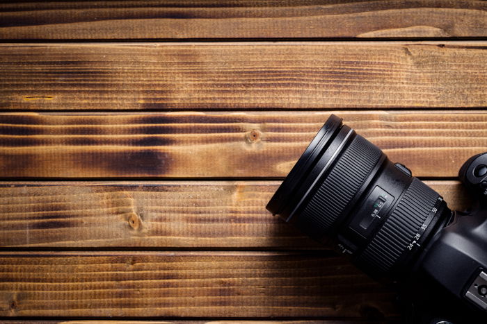 Professional camera with lens on wooden table.