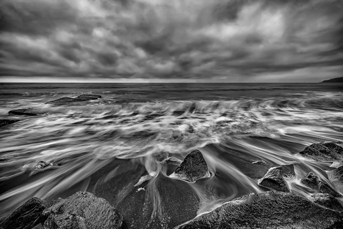 a black and white long exposure image of a seascape