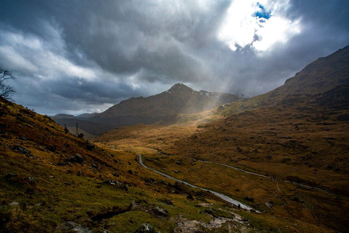 cloudy day photograph of a ray of light cutting through clouds onto a valley