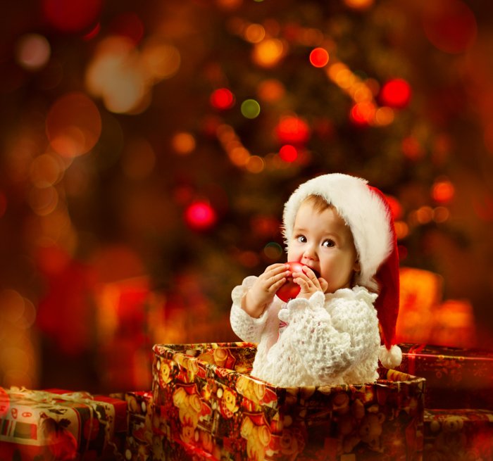 Sweet Christmas photo of a baby in a gift box in front of the christmas tree