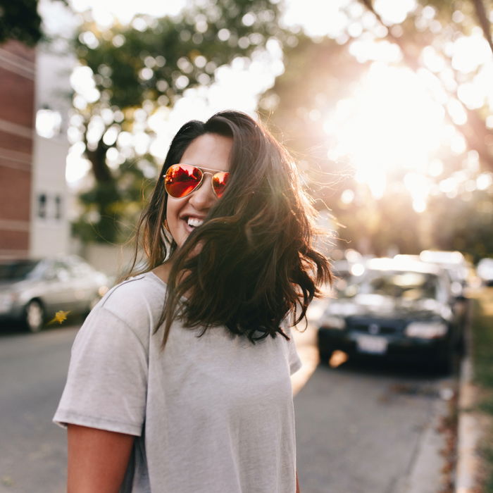 an image of a woman in sunglasses on a city street with setting sun backlighting