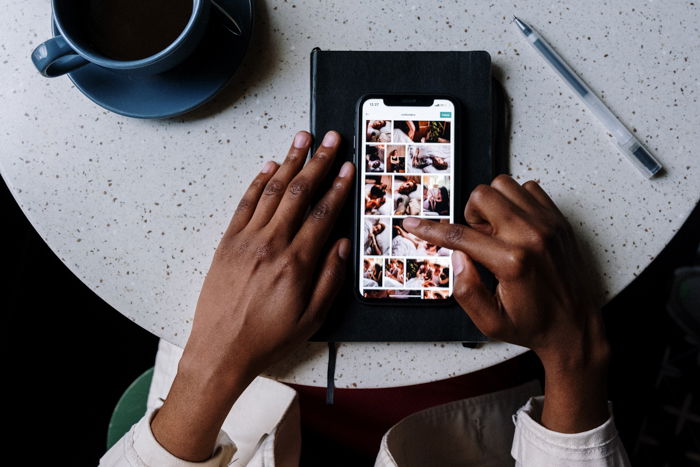 an overhead image of tow hands scrolling through a smartphones photos