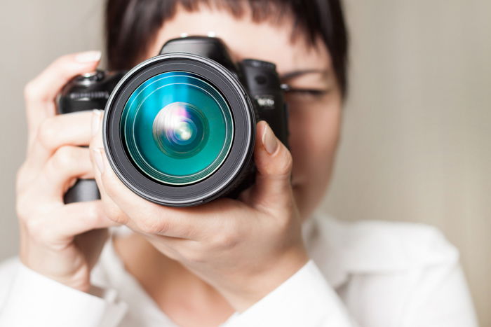 Closeup of a woman holding a camera and shooting with it. 