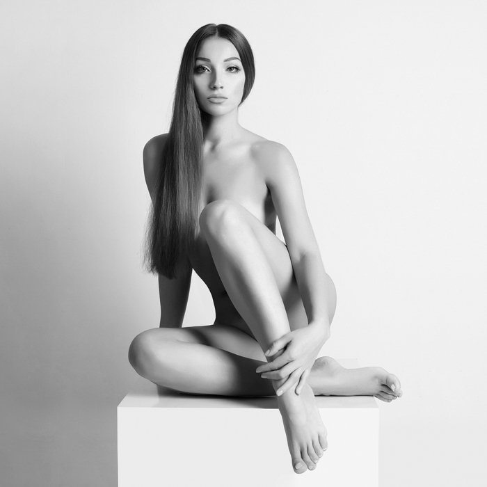 Boudoir portrait of a naked girl posing on a plinth