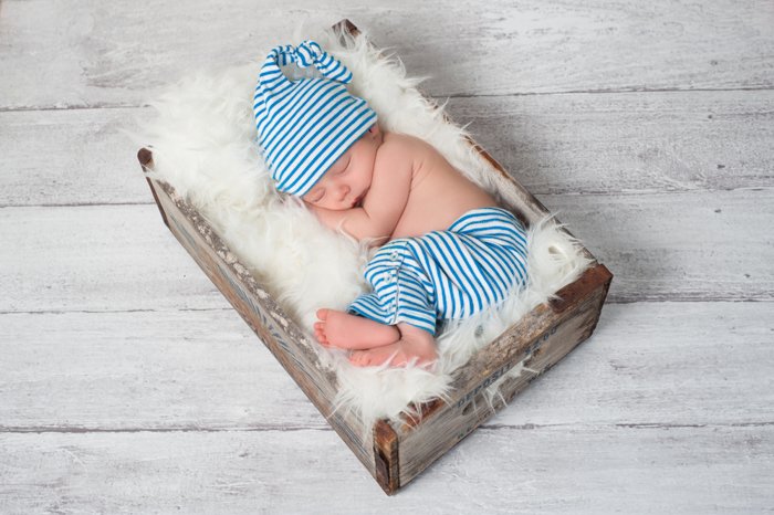 a top down shot of a newborn sleeping in a wood and feather box
