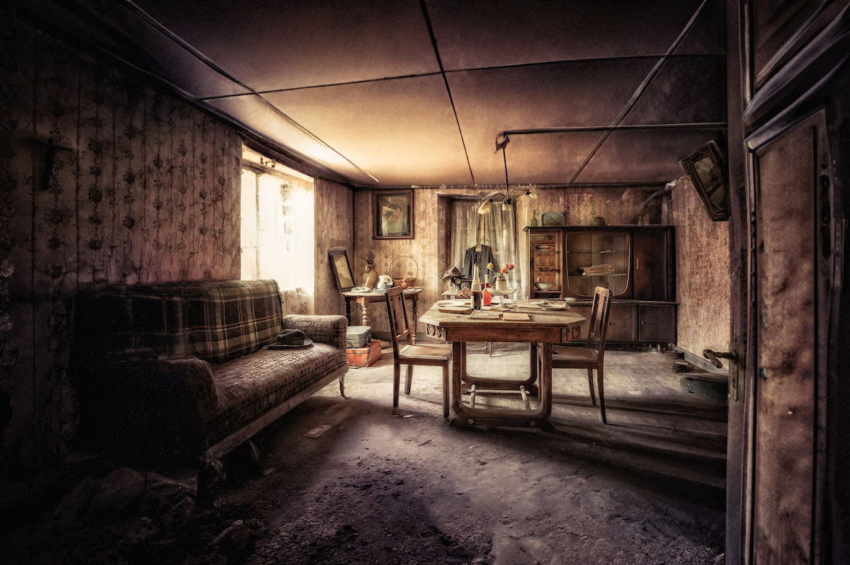 An abandoned living and dining room with furniture