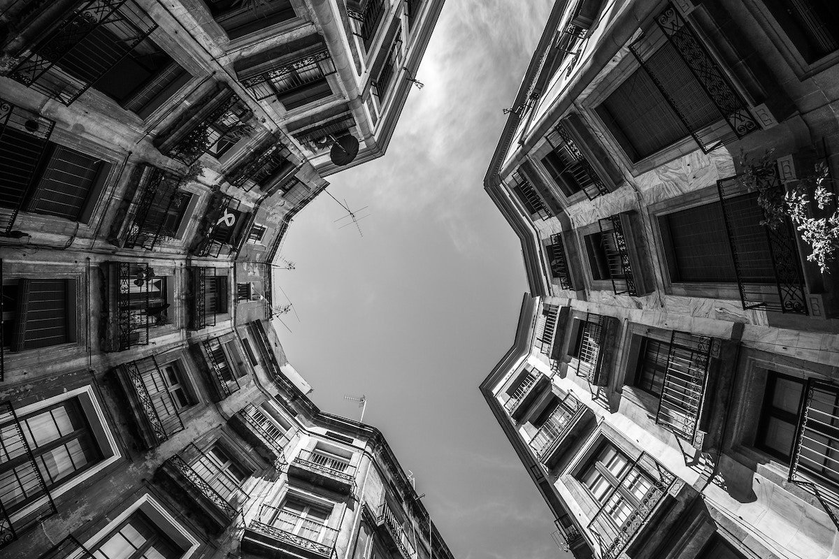 Black-and-white, circular, fish-eye shot of Carrer de Milans buildings and sky shot from below in Barcelona, Spain