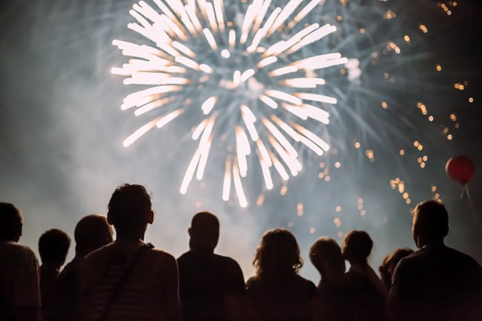 A crowd of people watching fireworks exploding in the night sky