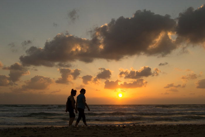 People walking on the beach at sunset