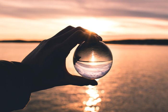 A person holding a crystal ball in front of a sea landscape