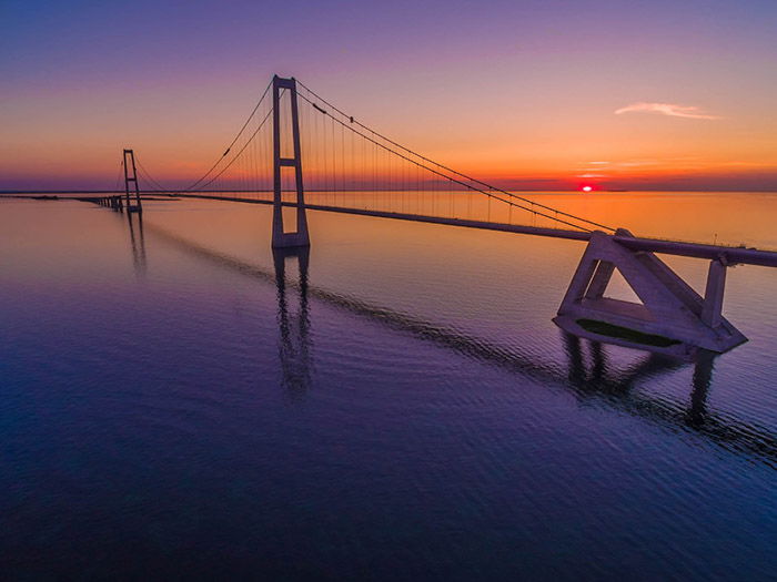 a drone photography image of a bridge across water at sunset