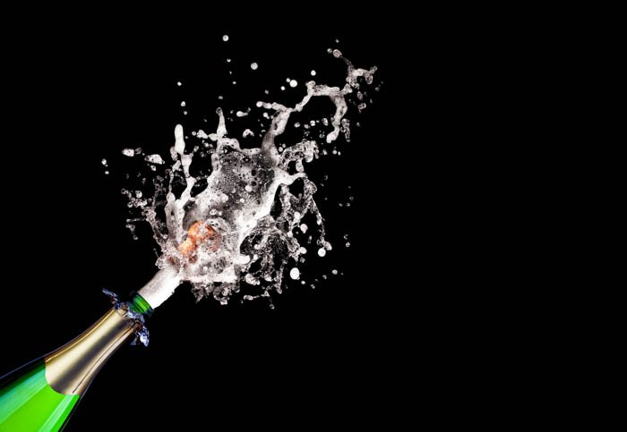  Popping champagne on black background