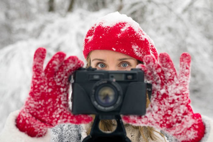 Girl holding a camera in her hands while wearing photography gloves