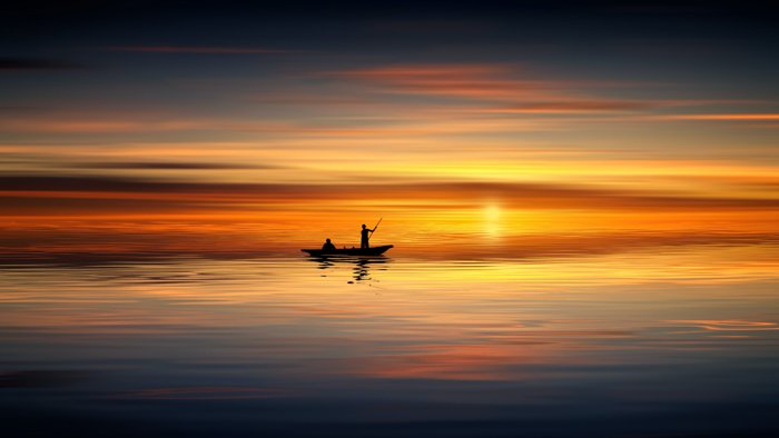 The silhouette of men in a boat at sunset