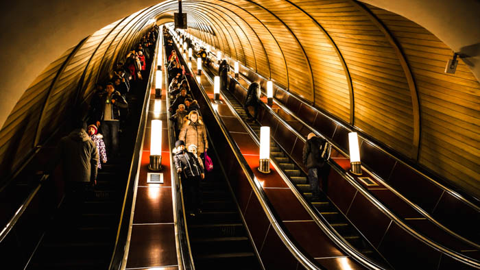 Deep subway station is crowded with people riding the escalators