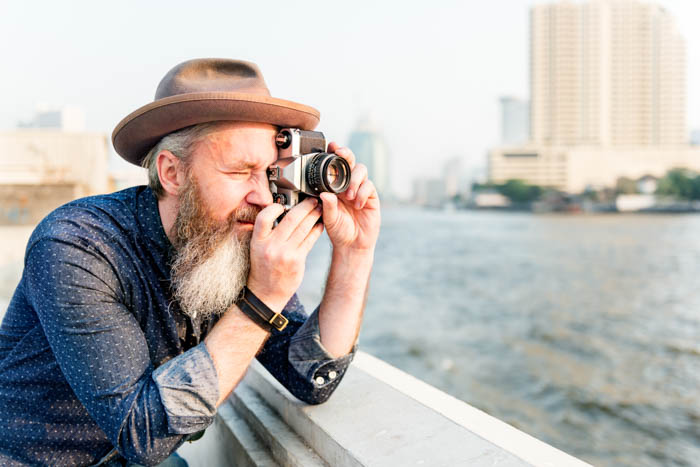 An image of an old traveller taking a picture with film camera