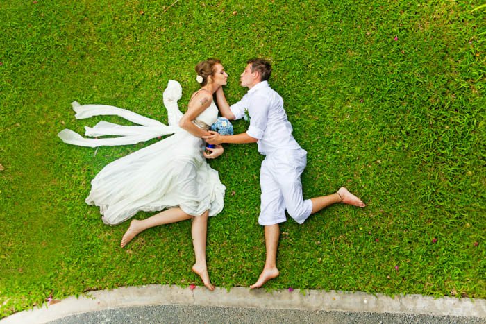 Couple laying on a green grass while imitating a jump shot from flat lay angle