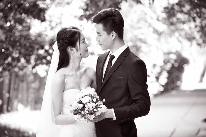 Outdoor portrait of asian bride and groom, happy and smiling, black and white.
