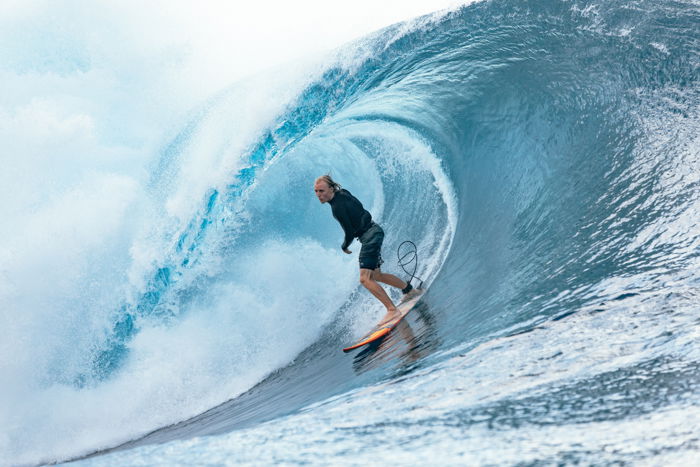 Fotografia de aventura de um surfista em uma onda azul.