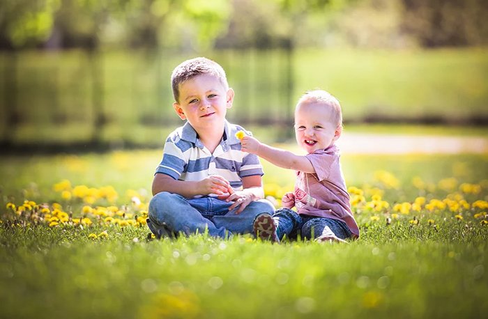 A photo of two happy child playing with each other in the grass.