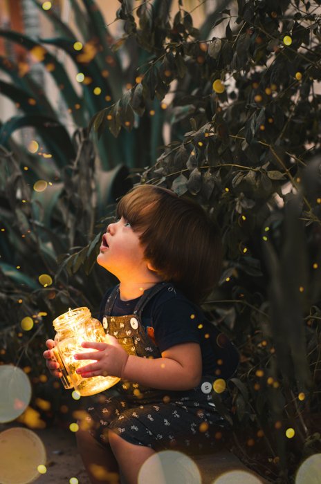 A magical child photography of a little boy surrounded by fairy bokeh lights.
