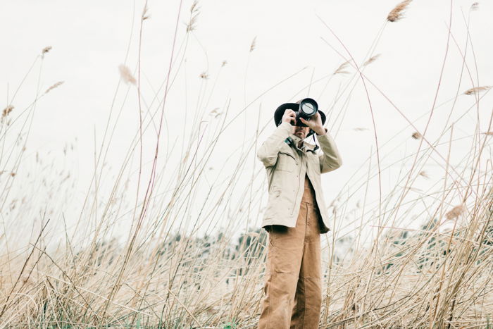 an image of a man in a wheat field holding a camera to his face