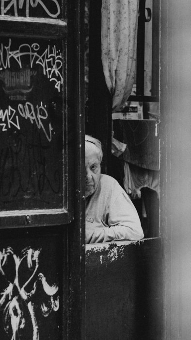 black and white image of an old person peeping at the camera