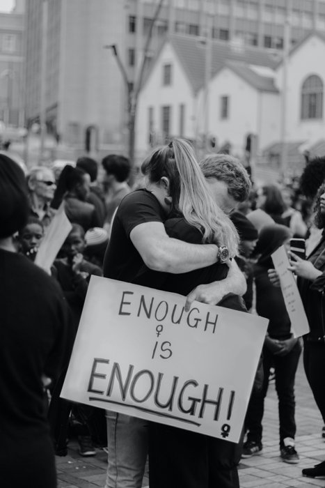 black and white image of two people hugging during a protest